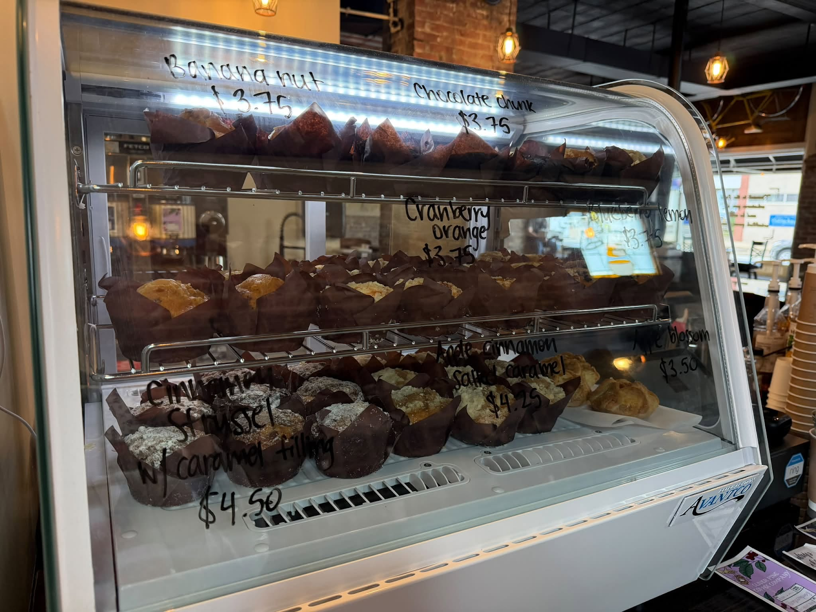 Bakery case of muffins and apple blossom pastries